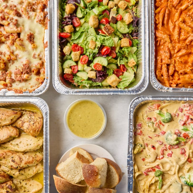 Six catering trays of various dishes, including pasta, salad, chicken, and bread, from Philly's Best.