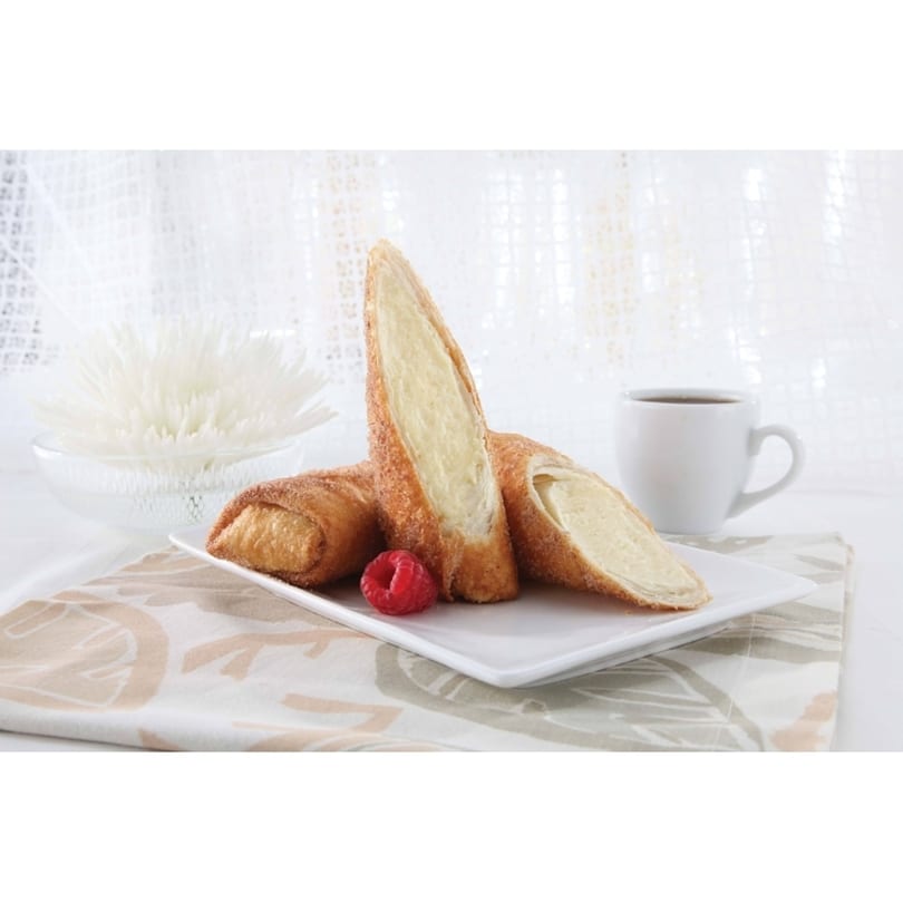 Three golden-brown dessert rolls, one cut open to show creamy filling, with a raspberry, coffee, and flower.