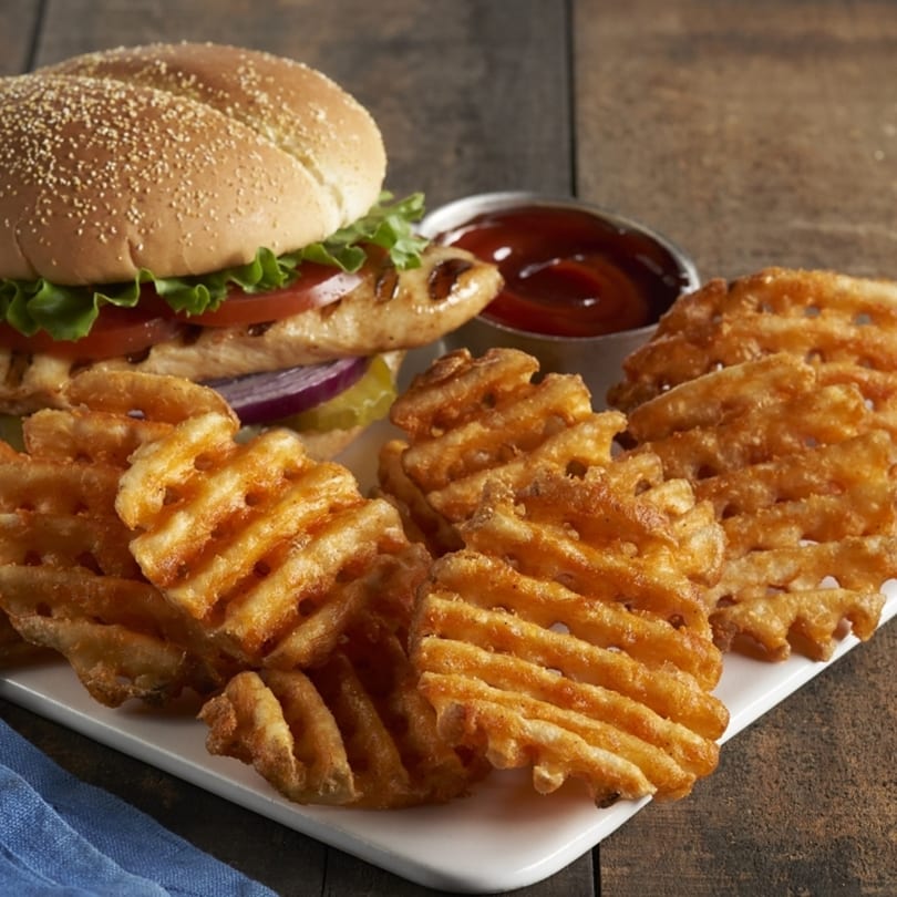 Grilled chicken sandwich with lettuce, tomato, onion, and pickles, served with waffle fries and ketchup.