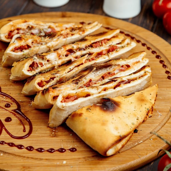 Philly's Best Pizza & Subs stromboli, sliced and filled with pepperoni and cheese, on a wooden board.